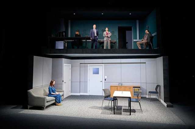 Un groupe d'acteurs sur un ensemble de théâtre qui ressemble à un design de bureau à deux étages