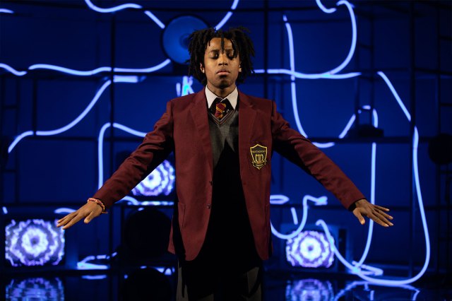 A young actor on stage in a school uniform