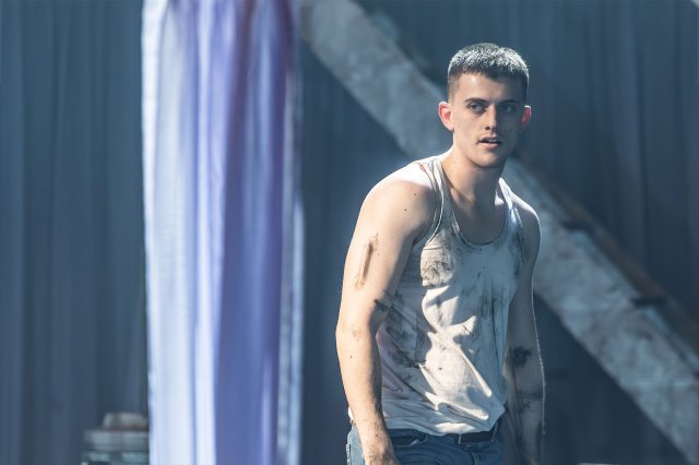 Un acteur se tient sur scène dans un gilet blanc sale