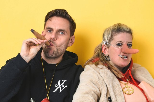 Un homme fumer un cigare et une femme portant un faux nez long