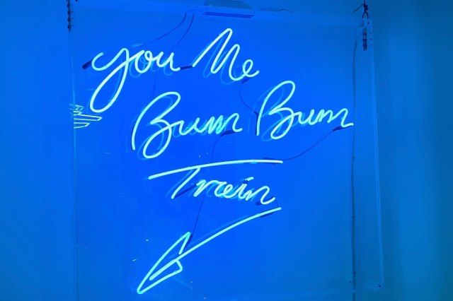 A blue neon sign that reads "You Me Bum Bum Train"