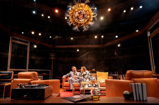 Un acteur et une actrice assis sur un salon set sur scène