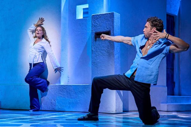 Izi Maxwell (Sophie) and Ben Irish (Sky) - she leans against a wall while he poses towards her
