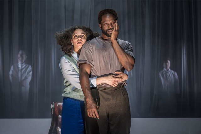 An actress puts her arms around the waist of an actor on stage