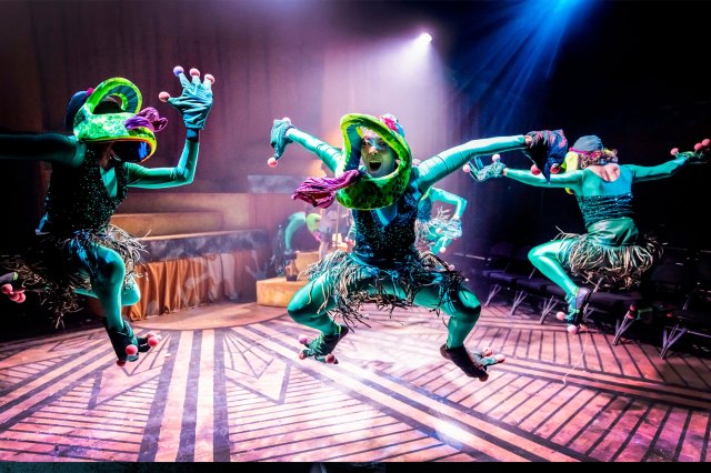 Quatre acteurs sur scène, vêtus de grenouilles sautant dans les airs