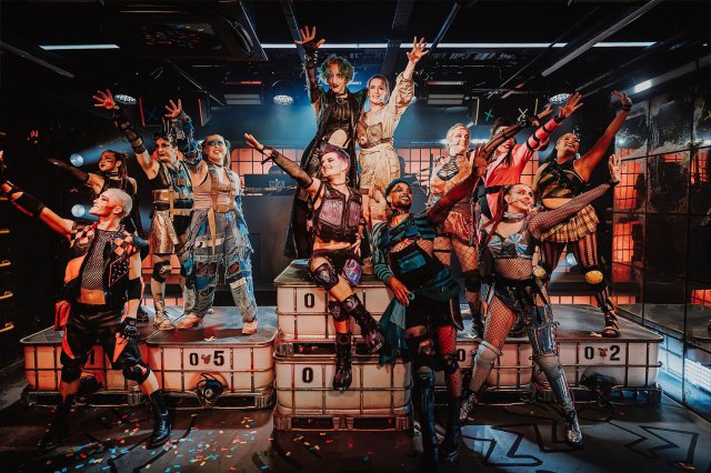 Un groupe d'acteurs en costumes dystopiques dans une boîte de nuit