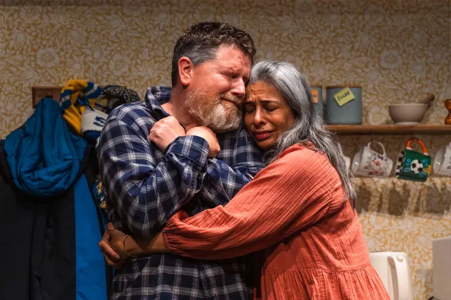 An actor and an actress embrace on stage.