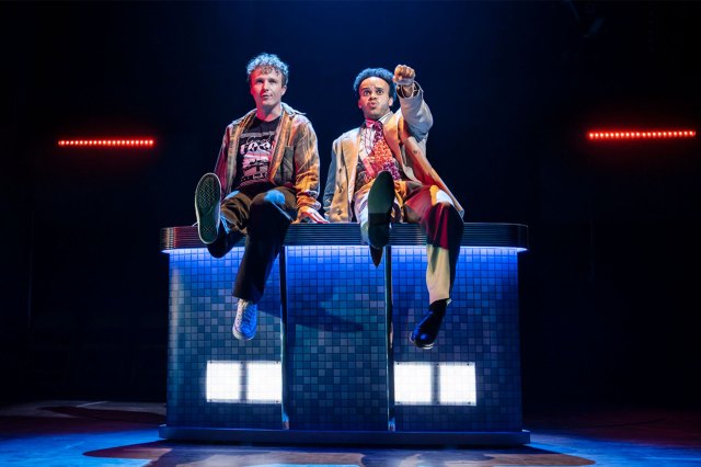 Two actors sitting on stage by the side of a swimming pool