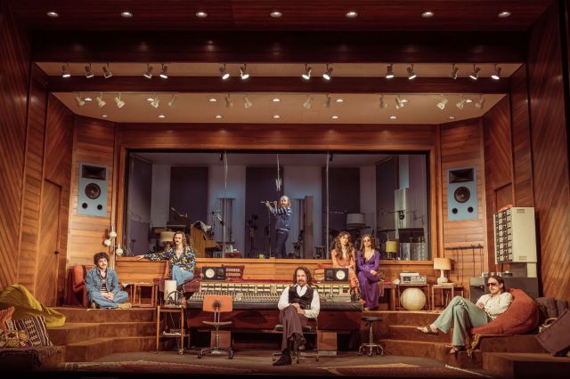 A scene from a play depicting a rock band and a sound engineer in a recording studio.