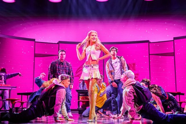 Regina George pose dans une cafétéria du lycée pendant que ses pairs regardent
